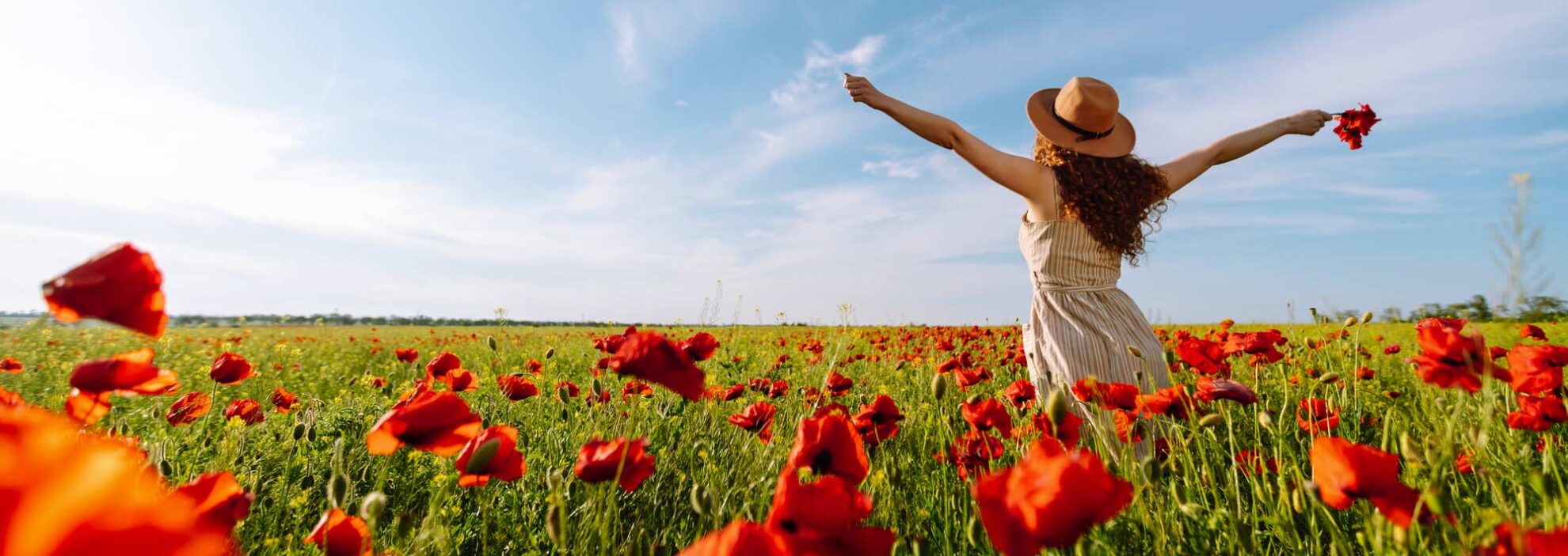 Frau steht im Mohnfeld und es ist Frühling